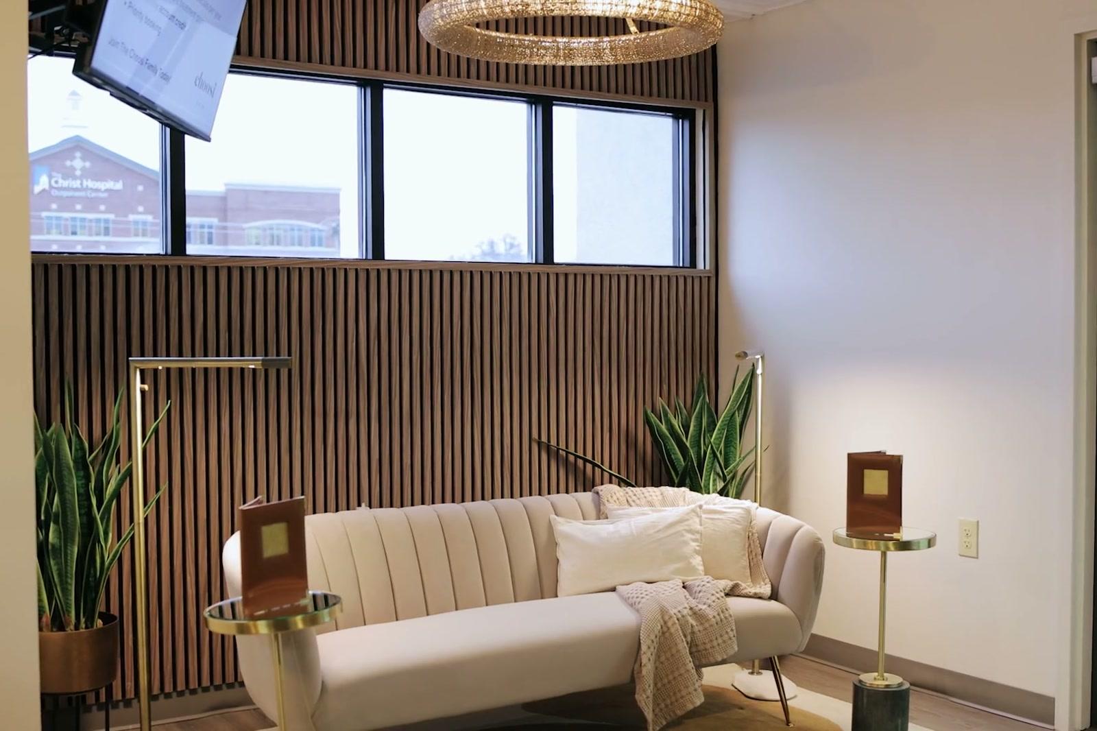 The lounge at Choosi, walnut slat wall behind a sofa with brass side tables under the window