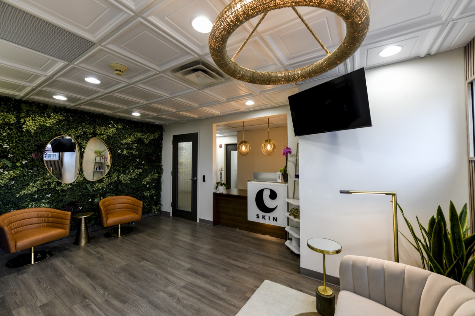 The living green wall at Choosi, with two oval gold mirrors and tan leather chairs